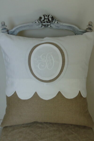 Housse de coussin avec feston en lin blanc et naturel, avec un médaillon et un monogramme. style romantique